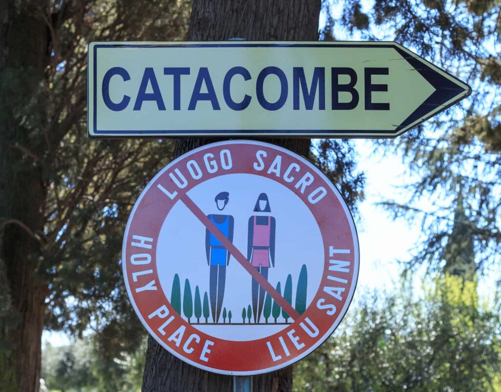 Cartello sulla via Appia con indicazioni per le catacombe e sul dress code